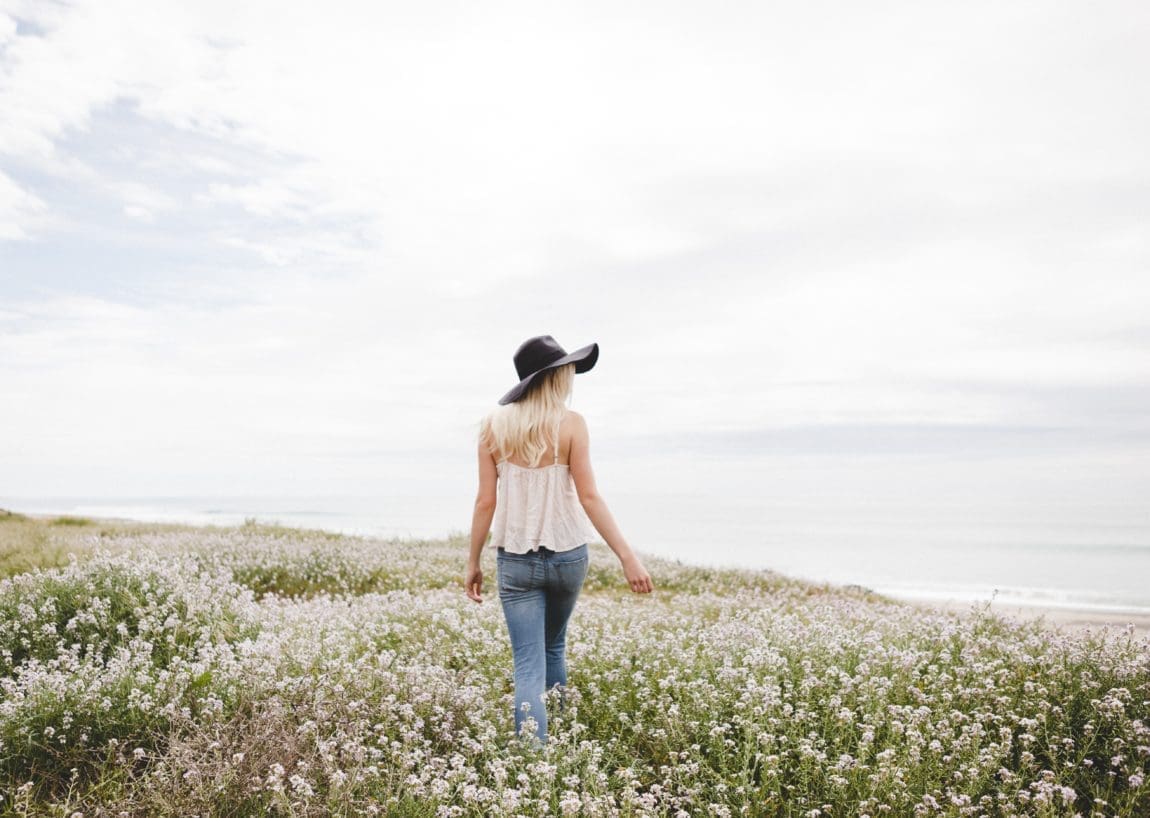 a woman walking in a field of flowers