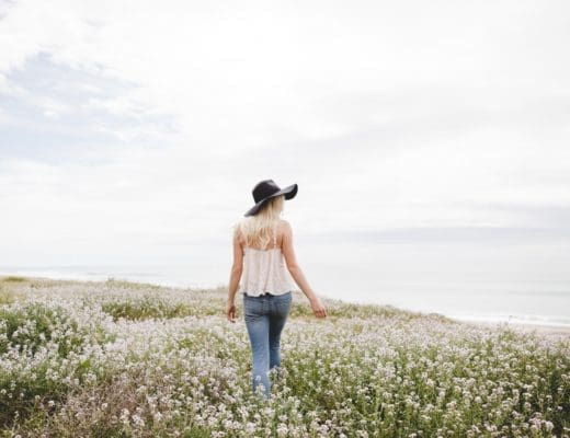 a woman walking in a field of flowers