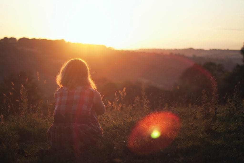 a woman looks out towards the sunset